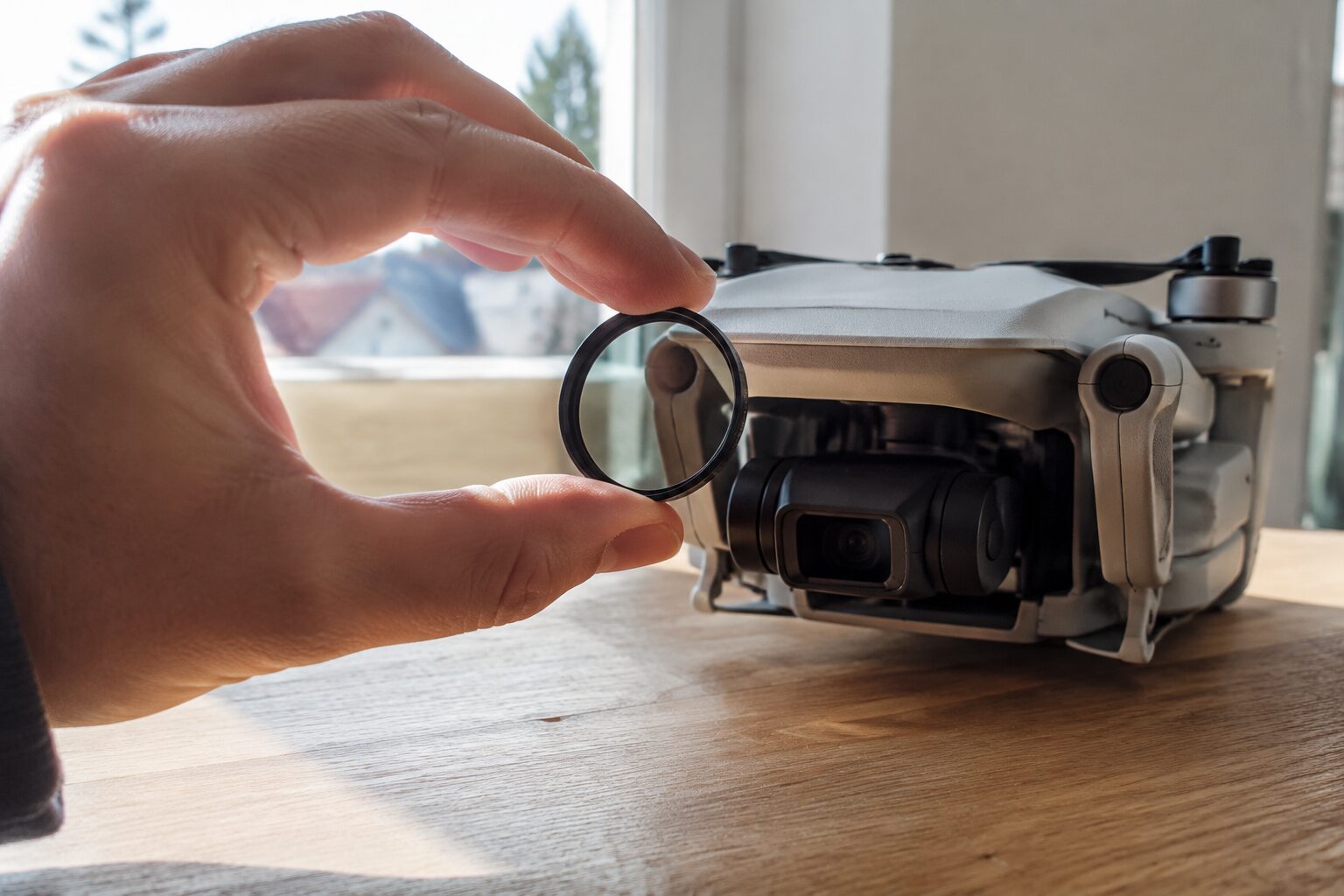 Een hand die een rond lensfilter voor een dronecamera houdt