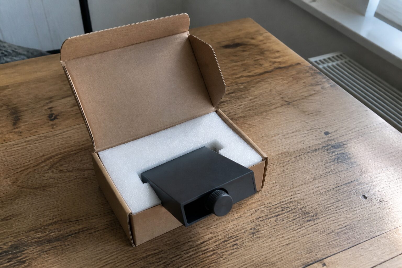 Een half uitgepakt kartonnen doosje met schuim en een accessoire dat er half uit steekt