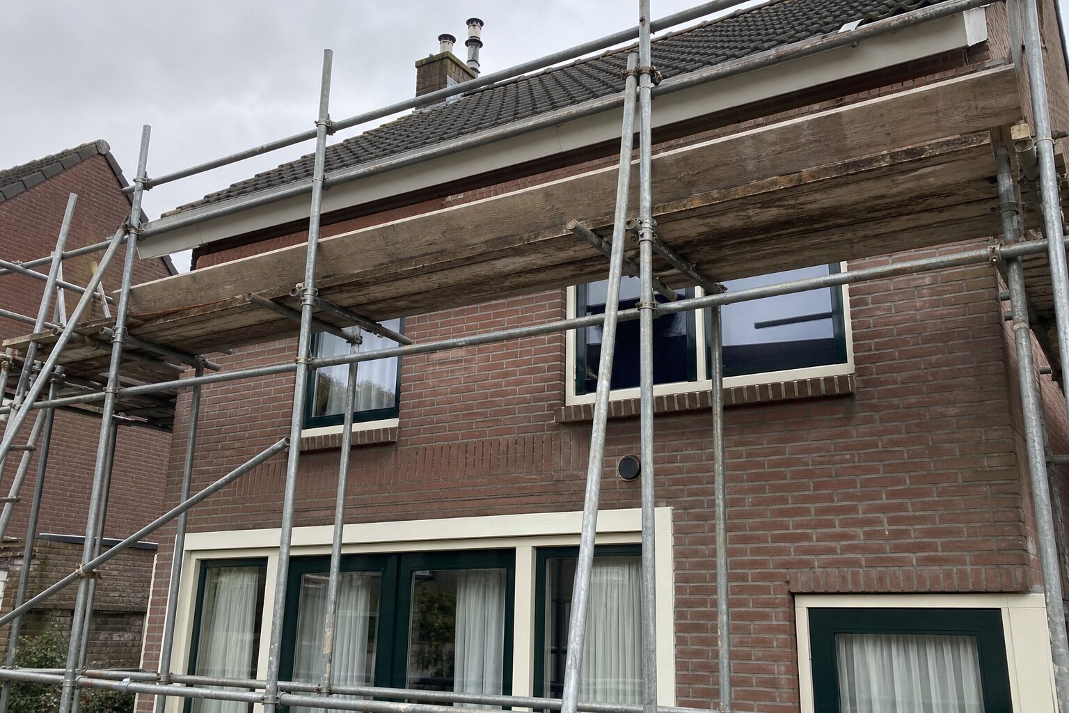 De gevel van een woonhuis met een steiger ertegenaan