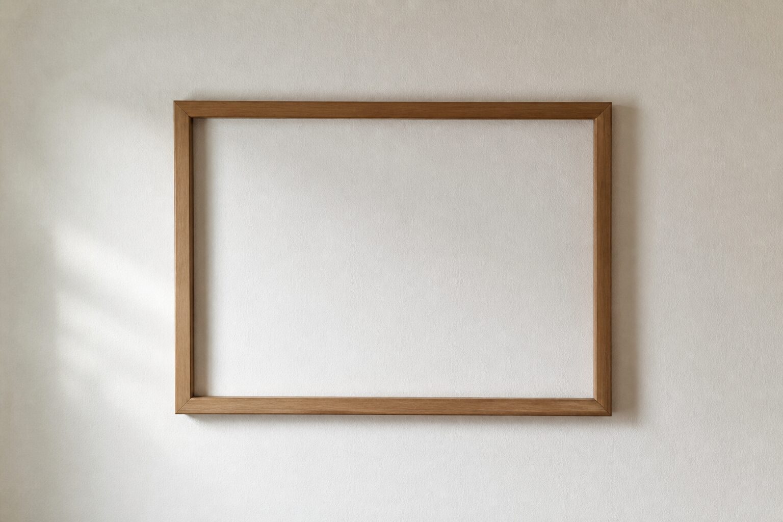Een enkele lege houten fotolijst aan een lichte muur